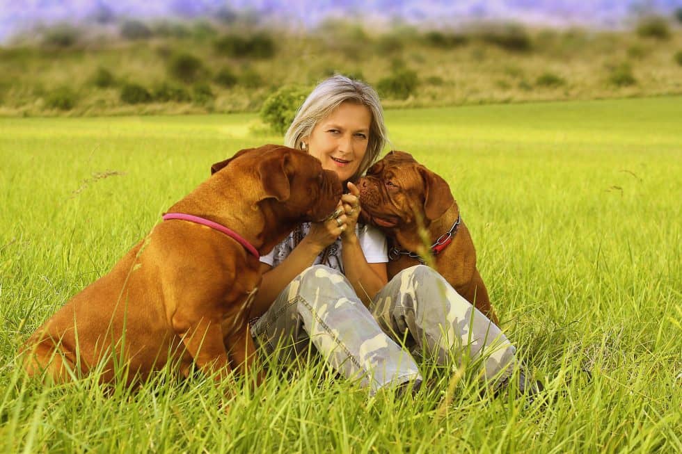 woman-receiving-kisses-from-two-dogs