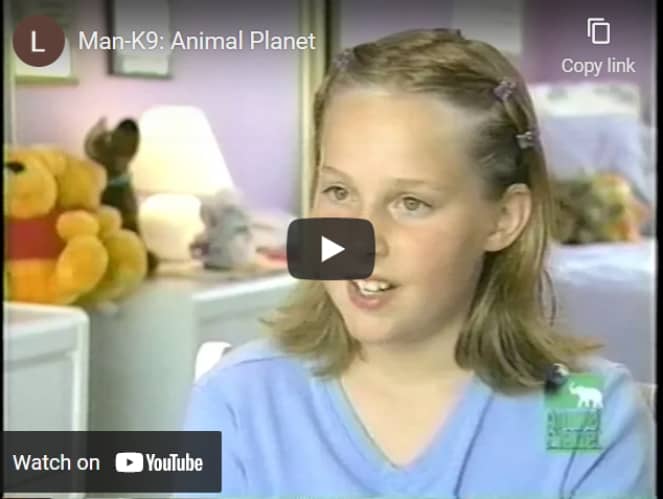 A girl with a hair clip speaking during a televised interview, with a play button indicating video content from animal planet.